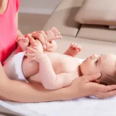 Sanfte Hände untersuchen die Füße eines Babys. Eine Mutter fragt sich, wann mit Baby zum Osteopathen gehen sollte, um solche Behandlungen zu erhalten.