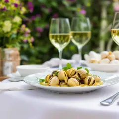 Un plat d'escargots à l'ail et au persil, servi avec des verres de vin blanc. La question est : quel vin avec les escargots ?