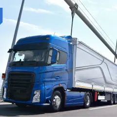 Niebieska ciężarówka z naczepą na moście, symbolizująca sprawną spedycję transport krajowy.