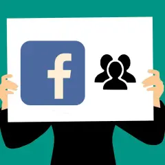 Logo Facebook i ikona grupy ludzi na plakacie. Ktoś trzyma go, prezentując się jako lider wśród fanów.