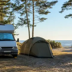 Kamper i namiot na piasku, w otoczeniu drzew, z widokiem na morze. Idealne miejsce na camping nad morzem.