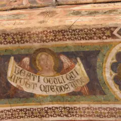 Angeli con pergamena negli affreschi dell'abbazia di Pomposa. Dettaglio di un volto angelico con ali e iscrizione latina, parte di un ciclo pittorico antico.