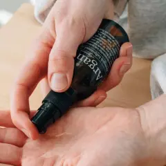 En hand pumpar ut arganolja i en annan handflata. Oljan är ekologisk och kallpressad.