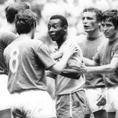 Słynny piłkarz brazylijski, Pelé, otoczony przez innych graczy, w geście sportowego szacunku po meczu.