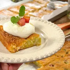 En saftig rabarberkaka i långpanna, toppad med fluffig grädde och färsk mynta. Perfekt för fikat!