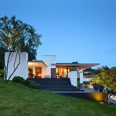 Moderne Villa mit breiter, dunkler Treppe zum Hauseingang. Tolle Ideen für Haus und Treppe, beleuchtet bei Dämmerung.