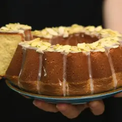 Pyszna babka z lukrem i płatkami migdałów, właśnie ukrojony kawałek kusi swoim wilgotnym wnętrzem.