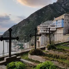 Cmentarz z krzyżami na tle klasztoru Athos i morza.