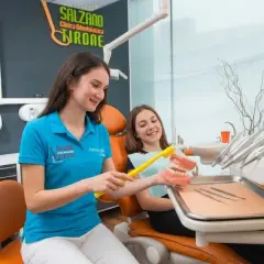 Dentista mostra a una bambina come lavarsi i denti su un modello. Scopri il detartrasi costo per un sorriso smagliante.