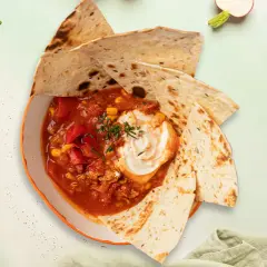 Meksykańska zupa sopa de tortilla z tortillą, śmietaną, kukurydzą i pomidorami.