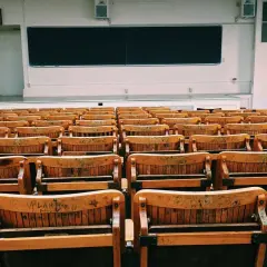Puste drewniane ławki w sali wykładowej, jakby czekające na studentów w futurystycznym francuskim uniwersytecie.
