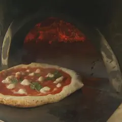 Eine authentische Pizza Napoletana mit Mozzarella und Basilikum wird in einem Holzofen gebacken.