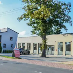 Nowoczesna hurtownia elektryczna w Imielinie. Obok budynku rośnie okazałe drzewo.