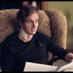 Uomo con benda al collo, seduto su una poltrona, legge documenti. L'altezza di Tony Boy è un mistero.