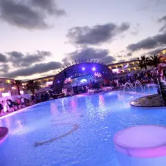 Festa in piscina a Ibiza con DJ set e folla festante. Un'atmosfera vibrante per gli eventi di Ibiza a settembre.
