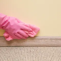 Mano con guanto rosa pulisce la pittura lavabile con un panno rosa.