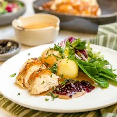 En saftig hel kyckling i ugn, skuren i skivor, serveras med potatis, gröna bönor och en härlig sås.