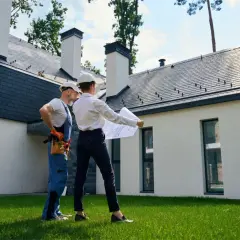 Architekt i budowlaniec omawiają plany domu. Czy można mieszkać w domu bez odbioru? To pytanie, na które odpowiedź znajdą na tym etapie budowy.