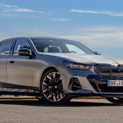 Srebrne BMW 520 z czarnymi akcentami stoi na tle błękitnego nieba i morza.
