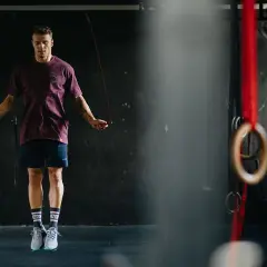 Mężczyzna w sportowym stroju skacze na skakance w siłowni.