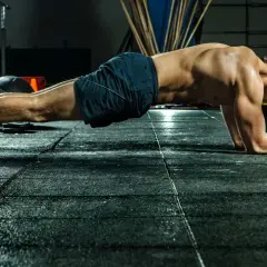 Mann im Fitnessstudio in Plank-Position, trainiert seinen Rumpf.