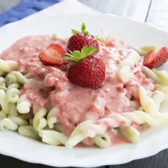 Makaron z truskawkami w kremowym sosie, ozdobiony świeżymi owocami.