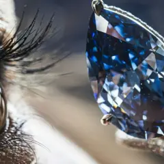Ein Auge blickt auf einen funkelnden blauen Diamanten, dessen Wert unermesslich ist.