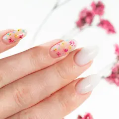 Delikatne, przezroczyste paznokcie z zatopionymi suszonymi kwiatami. Uroczy manicure w wiosennym stylu.
