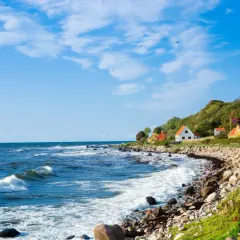 Malownicze domki na wzgórzu, duńska wyspa na Bałtyku, falujące morze i kamienista plaża.
