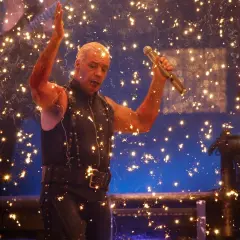 Till Lindemann z Rammstein śpiewa na koncercie, otoczony fajerwerkami.