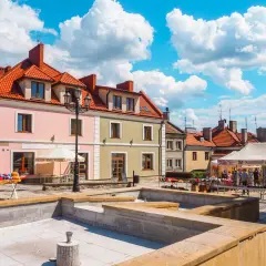 Sandomierz rynek tętni życiem. Kolorowe kamienice, stragany z pamiątkami i błękitne niebo tworzą malowniczy widok.