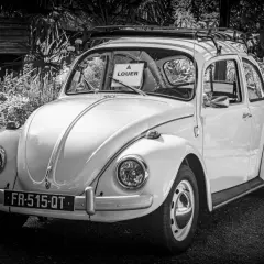 Klasyczny Volkswagen Garbus z tabliczką "À LOUER" na przedniej szybie. Idealny do kupna samochodu na wakacje.