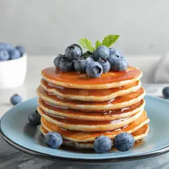 Pyszne, złociste pancake amerykańskie polane syropem i ozdobione świeżymi borówkami.