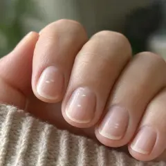 Dita con unghie naturali e una leggera ricrescita unghie dopo una settimana, con piccoli puntini bianchi visibili.