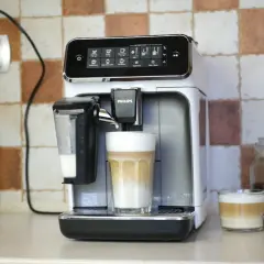 Philips LatteGo 3200 w trakcie czyszczenia obiegu mleka. Na blacie stoi ekspres, obok niego szklanka z kawą latte.