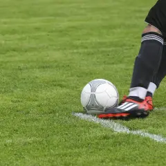 Piłkarz szykuje się do wykonania rzutu rożnego, przestrzegając zasad piłki nożnej. Piłka leży na linii bocznej boiska.