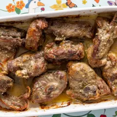 Pezzi succulenti di abbacchio alla romana cotti in teglia, dorati e profumati, pronti per essere gustati.