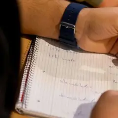 Schüler schreibt Sätze auf Deutsch. Hoffentlich gibt es bald mehr Gehalt für Lehrer, damit sie sich auf ihre Arbeit konzentrieren können.