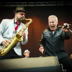 Stellan Sundahl sjunger med full kraft medan en saxofonist ackompanjerar.