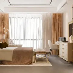 Elegancka sypialnia w kolorze kremowym z czym łączyć? Złote dodatki, brązowe zasłony i beżowe tekstylia tworzą przytulną atmosferę.