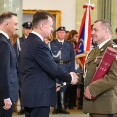 Uroczystość wręczenia nominacji generalskich. W centrum korpus generałów, prezydent Duda wręcza dokument.