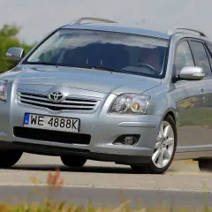 Srebrny kombi Toyota Avensis T25 z polskimi tablicami WE 4888K pokonuje zakręt na drodze, unosząc lekki pył.