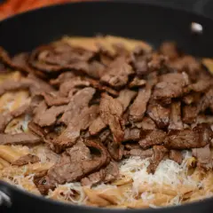 En krämig pasta i ugn med strimlat kött och riven ost.