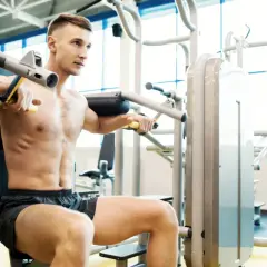 Mężczyzna na siłowni ćwiczy klatkę piersiową, czując przyjemną pompę mięśniową.