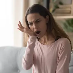 Donna con espressione sofferente, si tocca la guancia, manifestando un forte dolore diffuso a tutti i denti.