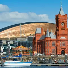 Bateaux amarrés dans le port de Cardiff, avec le bâtiment historique en brique rouge et le bâtiment moderne aux écailles cuivrées. Idéal pour visiter Cardiff.