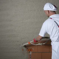 Tynkarz nakłada tynk cementowo-wapienny maszynowo. Kluczowe jest zapewnienie odpowiednich warunków, by tynk prawidłowo związał i wysechł.