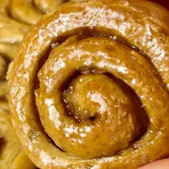 Un primo piano di soffici cinnamon rolls glassati, con la loro spirale invitante e il profumo di cannella che sembra quasi percepibile.