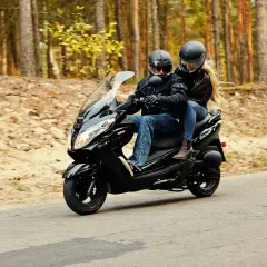 Para, ile waży skuter, para w kaskach jedzie czarnym skuterem przez jesienny las.