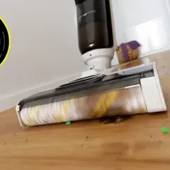Odkurzacz Karcher z obrotową szczotką zbiera zielone kuleczki i brud z drewnianej podłogi. Wyświetlacz pokazuje 100% baterii.